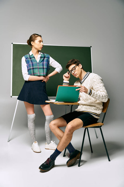 Elegantní studenti mužského a ženského pohlaví sedí před zelenou tabulí na vysoké škole. - Fotografie, Obrázek