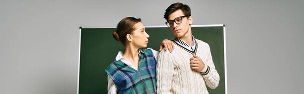 Bir üniversite ortamında yeşil bir panonun yanında duran şık bir kadın ve erkek.. - Fotoğraf, Görsel