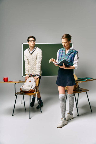 Un hombre apuesto y una mujer con estilo de pie junto a un tablero verde en un entorno universitario. - Foto, imagen