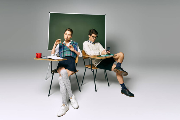 İki genç öğrenci, üniversite sınıfında yeşil bir panonun önünde masada oturuyor.. - Fotoğraf, Görsel