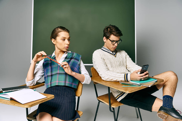 Elegáns férfi és nő ül előtt zöld tábla, részt vesz a tanulás. - Fotó, kép