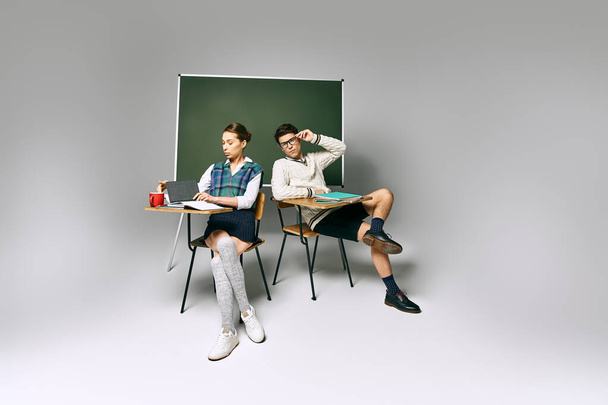 大学の設定で緑のボードの前に座っているエレガントな男性と女性の学生. - 写真・画像