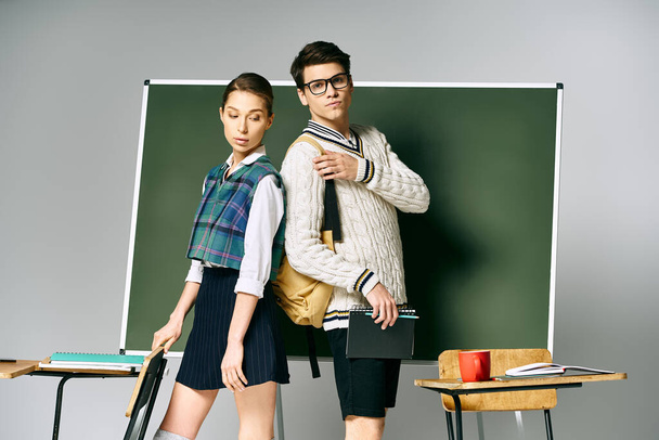 Un jeune homme et une jeune femme posent devant un tableau vert au collège. - Photo, image
