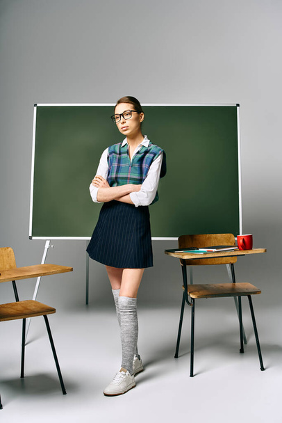Студентка в шкільній формі стоїть перед зеленою дошкою в коледжі. - Фото, зображення