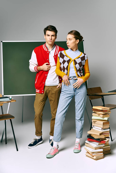 Un estudiante y una alumna posan elegantemente frente a una pila de libros. - Foto, Imagen
