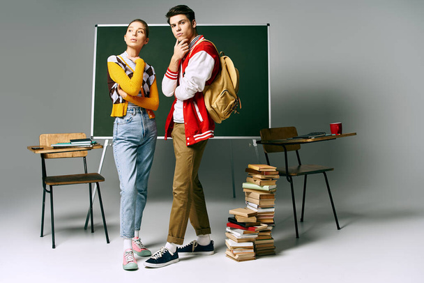 Két fiatal diák alkalmi öltözékben áll egy zöld tábla előtt egy főiskolai osztályteremben.. - Fotó, kép