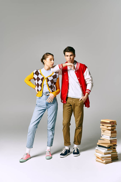 Jóvenes estudiantes masculinos y femeninos abrazándose mientras posan junto a una pila de libros en el aula universitaria. - Foto, Imagen