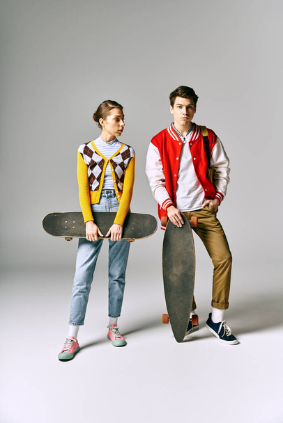 Dois jovens adultos elegantes seguram skates na frente de um cenário branco. - Foto, Imagem