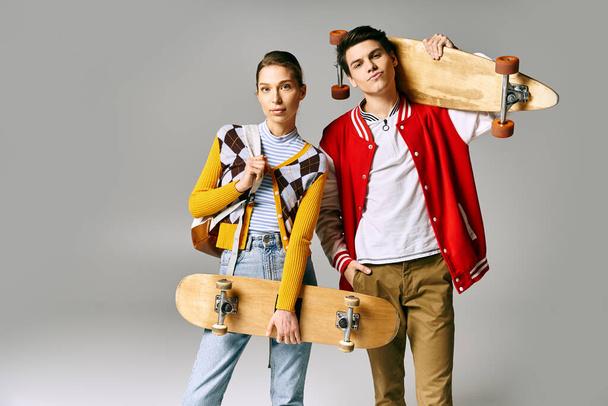 Δύο νέοι άνθρωποι κατέχουν skateboards σε γκρι φόντο. - Φωτογραφία, εικόνα