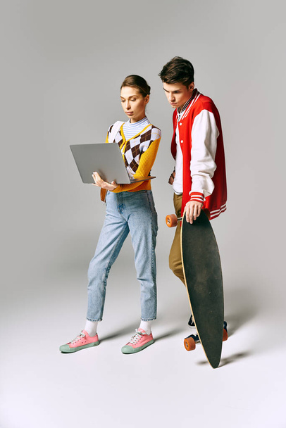 Młodzi studenci z deskorolką i laptopem, emanujący chłodnymi przypadkowymi wibracjami w środowisku studenckim. - Zdjęcie, obraz