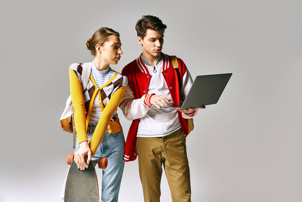 Fiatal férfi és női diákok állnak össze, egy laptopot tartva egy főiskolai osztályteremben. - Fotó, kép