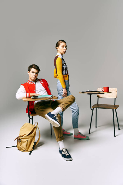 Un homme et une femme, étudiants, assis sur un bureau dans une salle de classe, absorbé par la conversation. - Photo, image