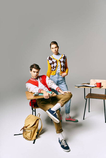 Jeunes étudiants hommes et femmes en tenue décontractée posant devant un bureau dans une salle de classe du collège. - Photo, image