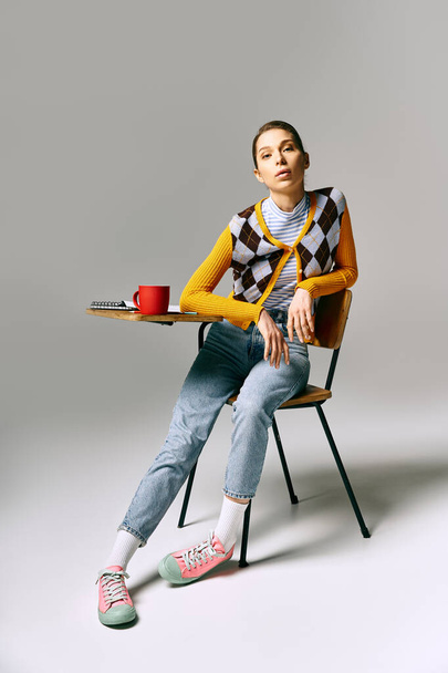 Μια γυναίκα κάθεται σε μια καρέκλα, με ένα φλιτζάνι καφέ. - Φωτογραφία, εικόνα