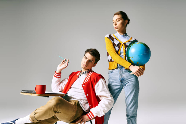 Un maschio e una femmina studenti siedono in possesso di un globo, nel profondo del pensiero e della meraviglia. - Foto, immagini