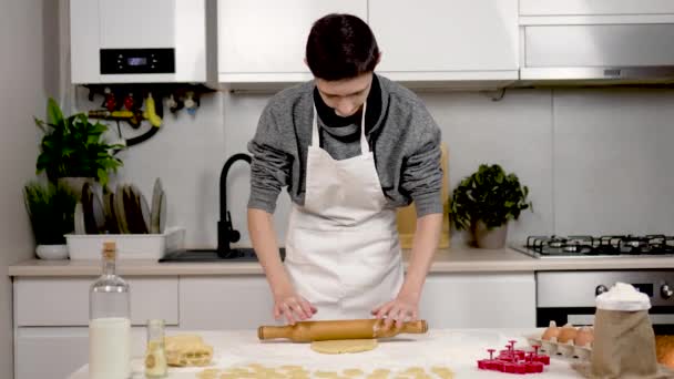 Portrait of boy rolls dough with rolling pin on table. Kitchen with ingredients of flour eggs milk sugar for shortbread cookies with help of figures for carving dessert products for happy childhood - Footage, Video