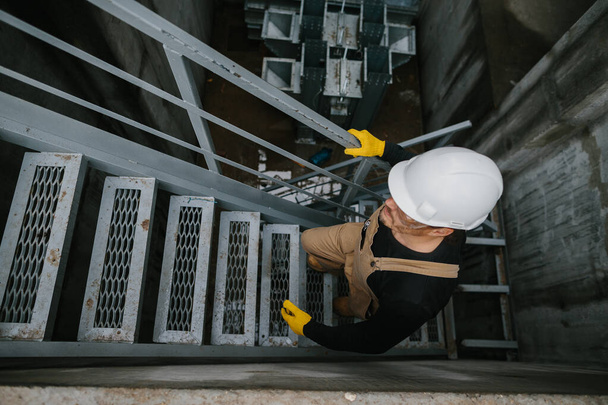 Vue de dessus de l'ouvrier d'usine montant des escaliers en métal sur le bâtiment de silo industriel - Photo, image