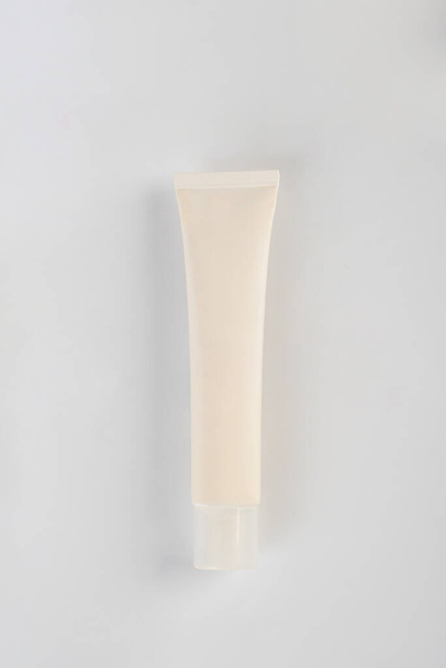 Plastic white tube for cream or lotion. Skin care or sunscreen cosmetic on pink background. - Photo, Image