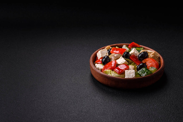 Köstlicher frischer, saftiger Salat aus Paprika, Käse, Oliven, Tomaten, Gurken mit Salz und Gewürzen auf dunklem Betongrund - Foto, Bild