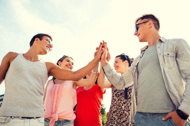 group of smiling friends making high five outdoors - Photo, Image