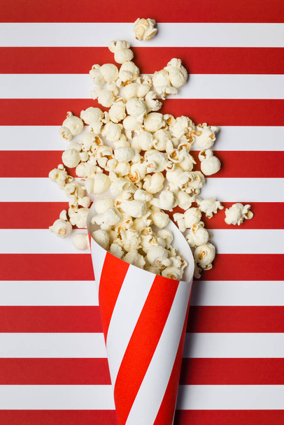 Płaska kompozycja układania z popcornem na tle czerwono-białych pasków. - Zdjęcie, obraz