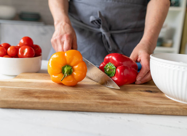 Woman preparing bell peppers on a cutting board in the kitchen. Healthy food - Photo, Image