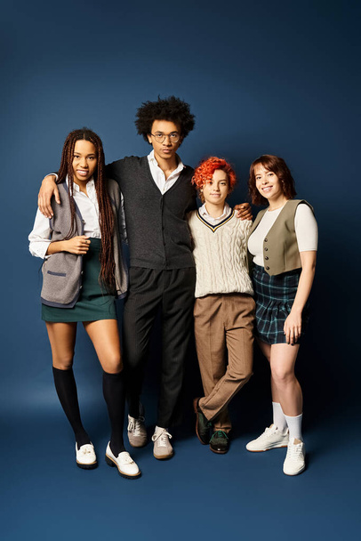 Fiatal barátok sokszínű csoportja, köztük egy nem bináris személy, akik elegáns öltözékben állnak sötét kék háttérrel. - Fotó, kép