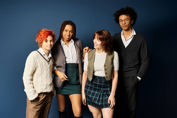 Un groupe diversifié de jeunes amis, debout ensemble dans une tenue élégante sur un fond bleu foncé. - Photo, image