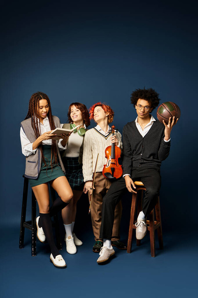 Multicultural young friends in stylish attire, including a nonbinary person, sitting closely together on a dark blue background. - Photo, Image