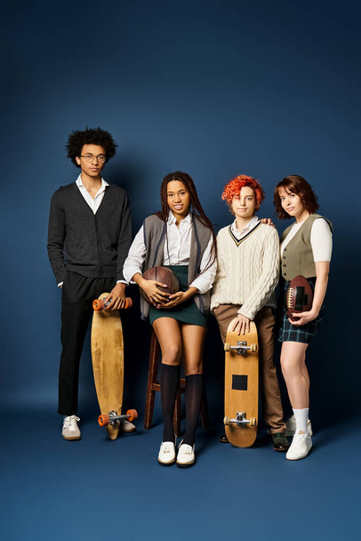 Multicultural friends, including a nonbinary person, stand in stylish attire, holding skateboards, against a dark blue backdrop. - Photo, Image