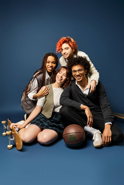 Een groep stijlvol geklede jonge multiculturele vrienden, waaronder een niet-binaire persoon, zitten dicht bij elkaar op een donkerblauwe achtergrond. - Foto, afbeelding