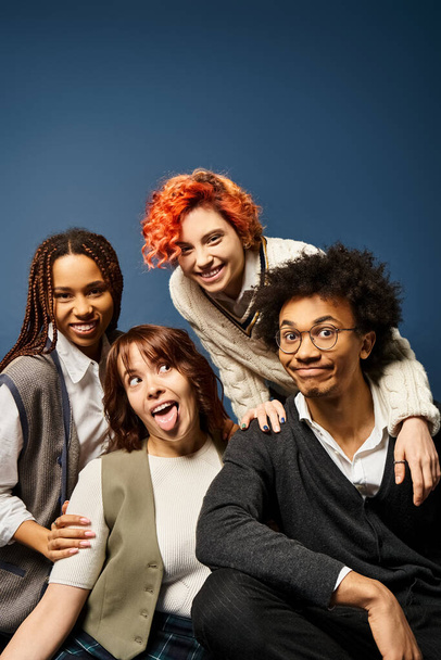 Les jeunes amis se tiennent ensemble dans une tenue élégante pour une photo de groupe sur un fond bleu foncé. - Photo, image