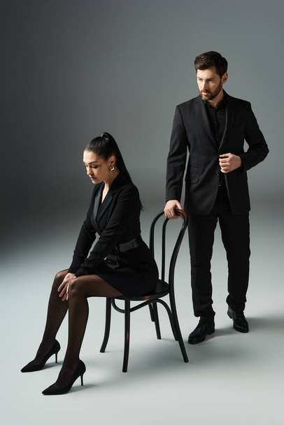 Мужчина и женщина в элегантной одежде обнимаются, сидя на стуле. - Фото, изображение