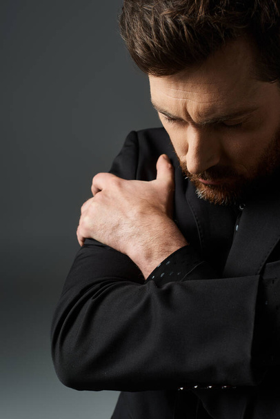 Ein Mann im schwarzen Anzug, die Hände zusammengeklammert. - Foto, Bild