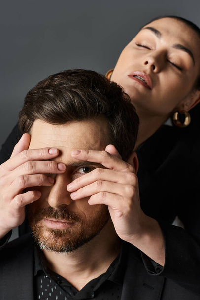 Woman in elegant attire covering eyes of her boyfriend with hands. - Photo, Image
