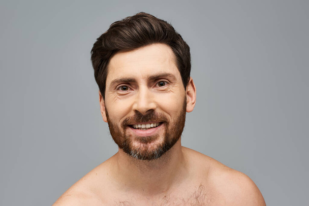 Um homem barbudo fica sem camisa, mostrando seu cabelo facial com confiança. - Foto, Imagem