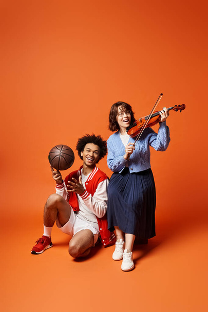Jovens amigos multiculturais posam com um basquete e um violino em um estúdio elegante. - Foto, Imagem