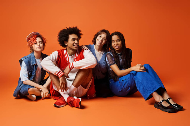 Eine Gruppe junger, multikultureller Freunde, darunter eine nichtbinäre Person, die in stilvoller Kleidung in einem Studio-Ambiente eng beieinander sitzen. - Foto, Bild