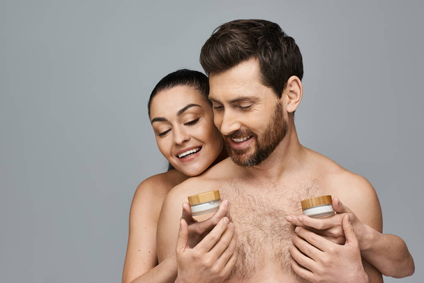 Un uomo e una donna in possesso di un barattolo di crema, applicando la cura della pelle. - Foto, immagini