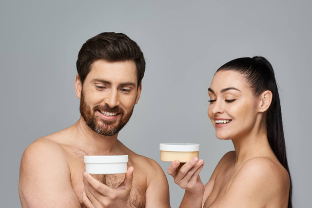 Un couple séduisant tient élégamment un pot de crème, mettant en valeur leur routine de soins de la peau. - Photo, image