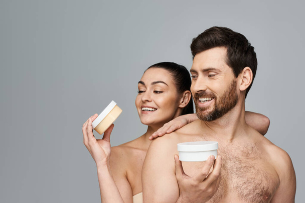 Jolly pareja elegantemente sostienen un frasco de crema, mostrando su rutina de cuidado de la piel. - Foto, Imagen