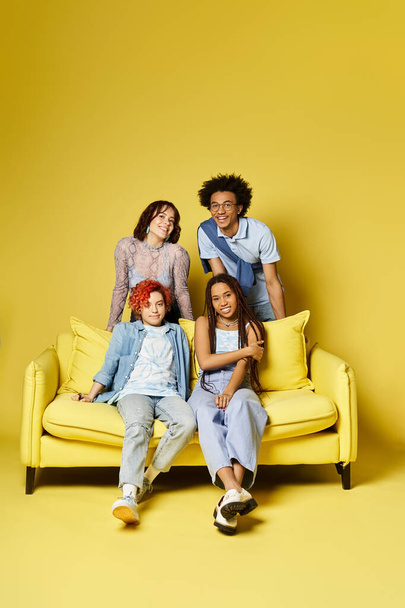 Πολυπολιτισμικοί φίλοι χαλαρώνουν σε ένα φωτεινό κίτρινο καναπέ σε ένα κομψό σκηνικό στούντιο. - Φωτογραφία, εικόνα