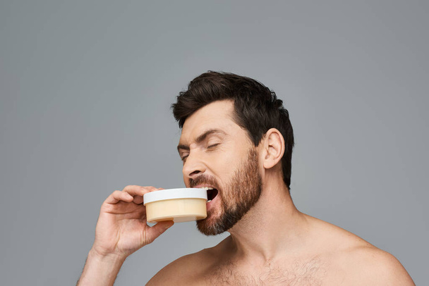Homme barbu mordant un pot de crème. - Photo, image