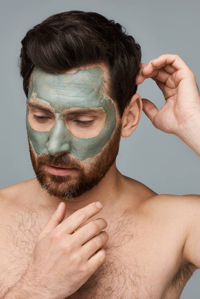 Un hombre aplicando mascarilla facial para el cuidado de la piel. - Foto, Imagen