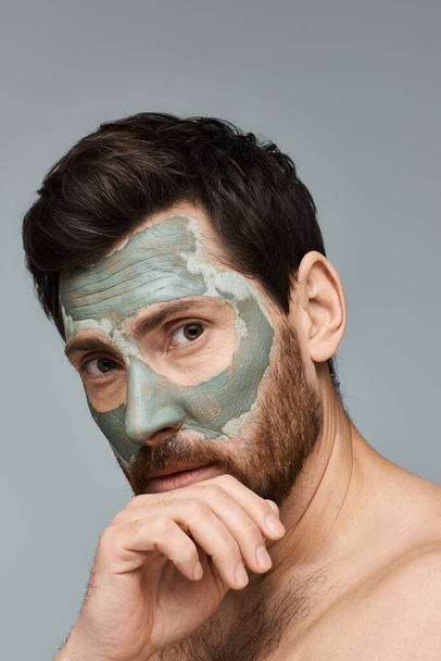 Mężczyzna w masce na twarz, poprawiający rutynę pielęgnacji skóry.. - Zdjęcie, obraz