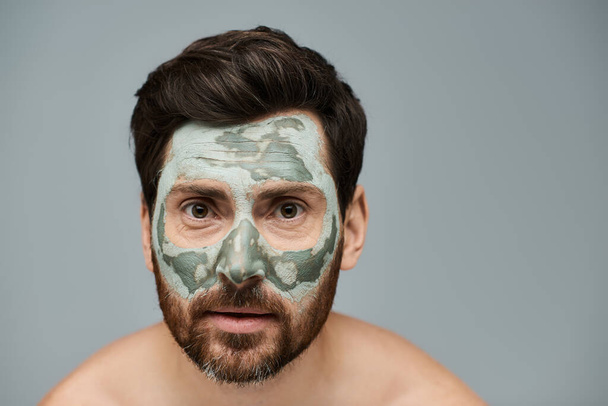 Γοητευτικός άντρας με μάσκα προσώπου, περιποίηση δέρματος. - Φωτογραφία, εικόνα