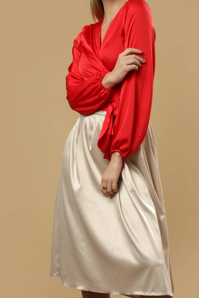 Serie von Studiofotos von jungen Models in seidensatinroter Bluse mit einfachem beigen Midirock. Bequeme und elegante Mode. - Foto, Bild