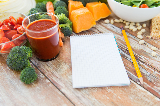 close up of ripe vegetables and notebook on table - Foto, afbeelding