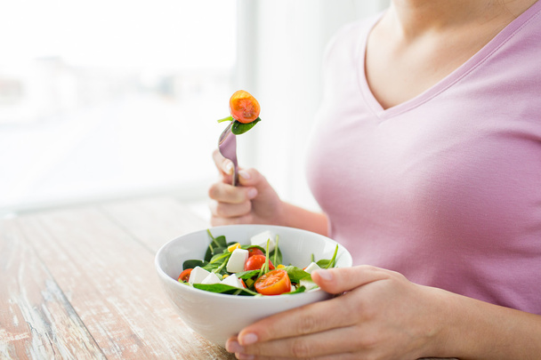 close up of young woman eating salad at home - Foto, Imagen