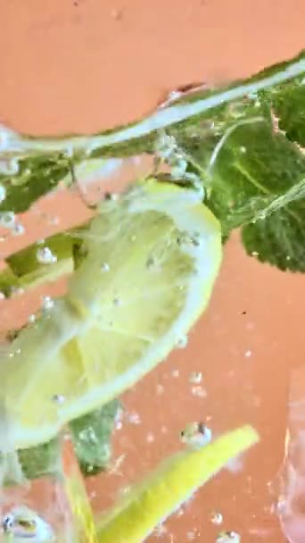 Plátky citronu a hvězdného ovoce s mátovými listy ponořené ve vodě s pruhovanou červenobílou slámou. Osvěžující limonáda. Struktura chladného sladkého letního nápoje. Koncept jídla, výživy, čerstvosti - Záběry, video